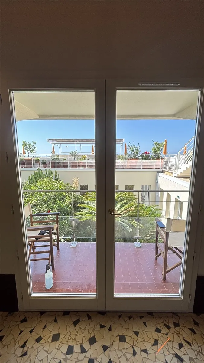 Porte-fenêtre avec film miroir sans tain vue de l'intérieur à Hyères, vue sur la terrasse et la mer préservée