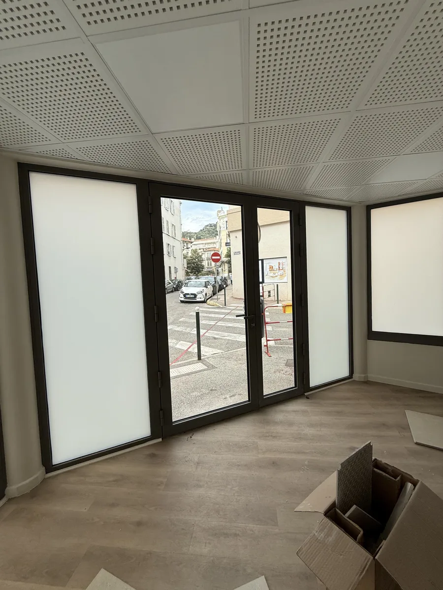 Le local commercial à Hyères après la pose : les vitrines dépolies encadrent la porte d'entrée, restée transparente pour l'accueil.