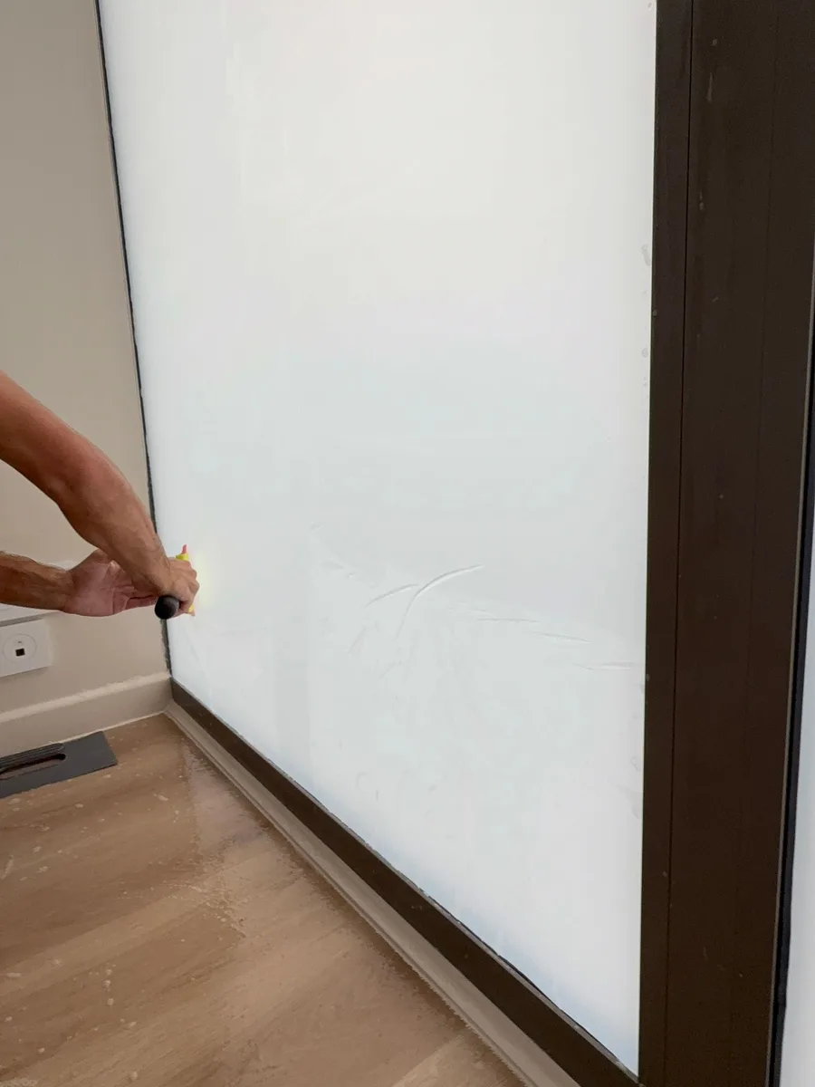 Finition du film dépoli au ras du joint de la vitrine, au cutter, par un technicien PrivTeint.