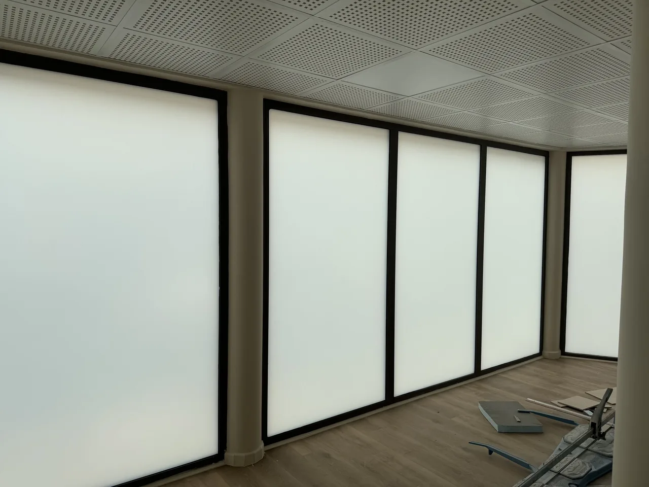 Grandes baies d'un local professionnel en film dépoli blanc : la lumière du jour traverse, le regard non