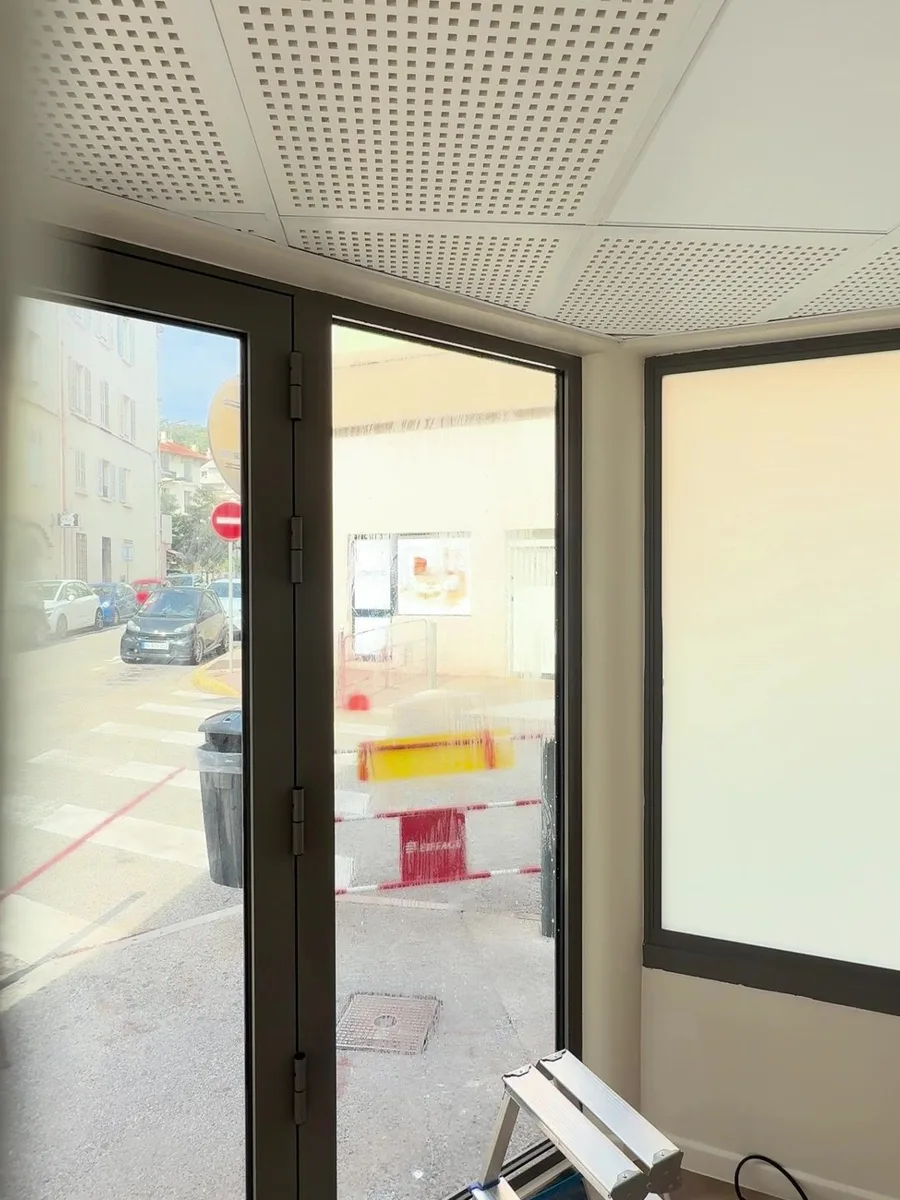Pose en cours dans le local commercial à Hyères : la porte vitrée encore transparente laisse voir la rue, tandis que le panneau voisin, déjà dépoli, devient blanc et opaque.