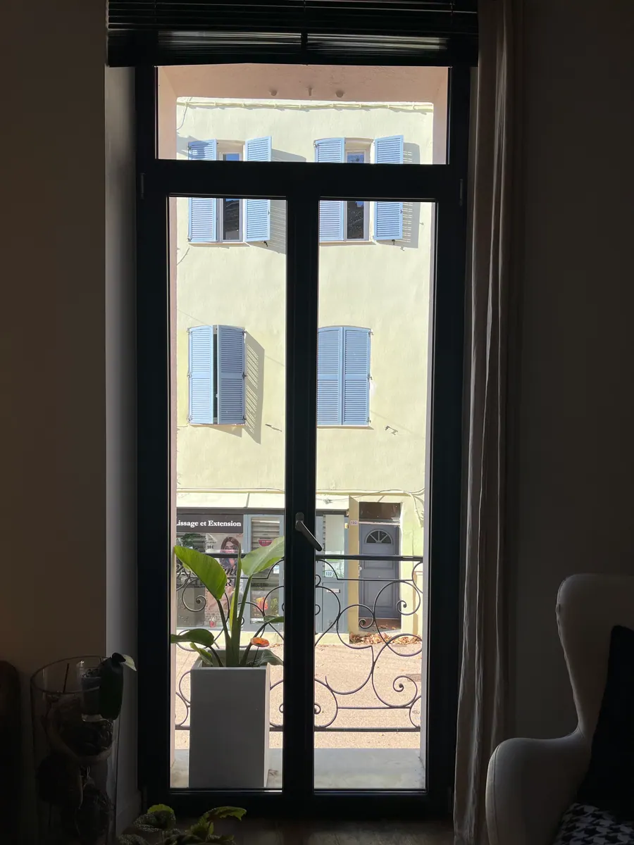 Avant la pose du film miroir sans tain à Saint-Raphaël : porte-fenêtre face à un immeuble aux volets bleus, vis-à-vis direct sur la rue