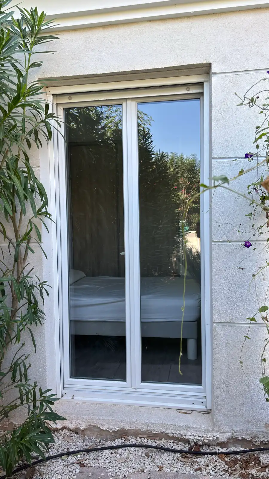 Avant : la baie vitrée de la chambre, à l'ombre, laisse voir le lit depuis le jardin.