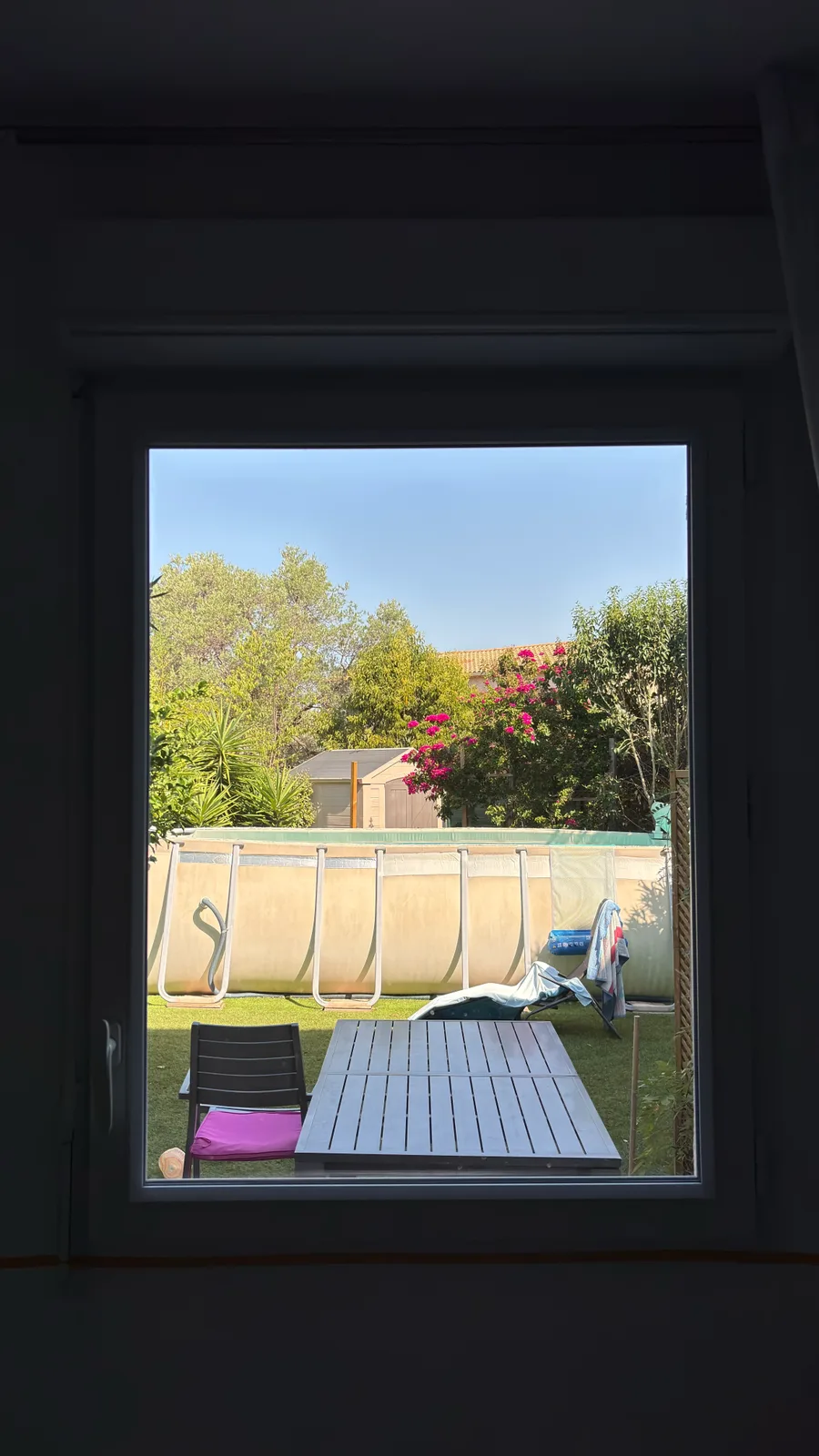 Avant la pose, vue depuis l'intérieur de la chambre : la fenêtre donne sur le jardin et la piscine.