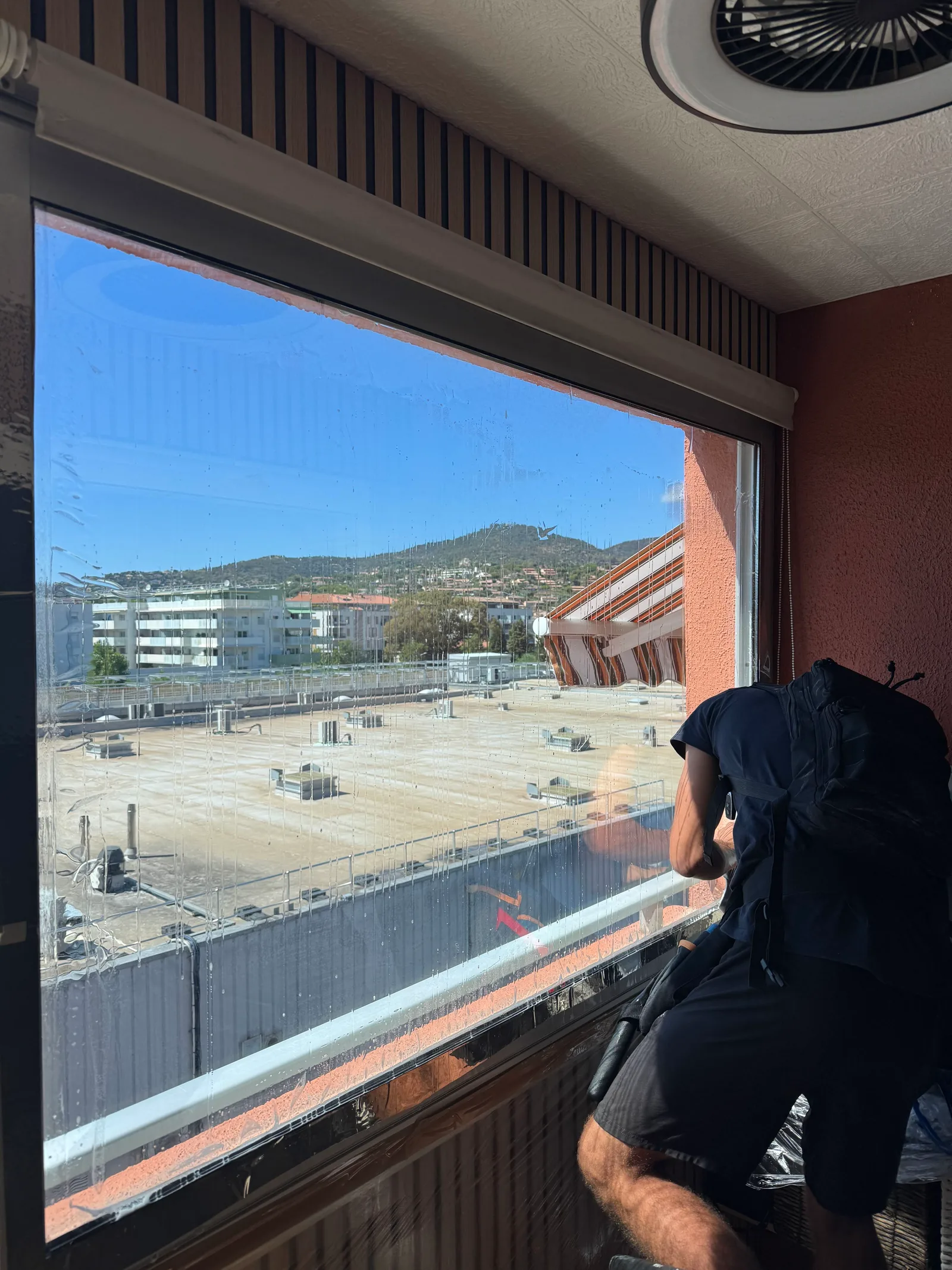 Pose d’un film anti-chaleur sur une grande fenêtre de bureau donnant sur une toiture-terrasse à Toulon