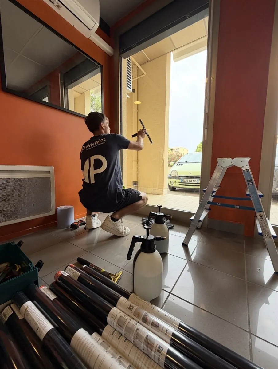 Technicien PrivTeint nettoyant et préparant une porte vitrée de commerce avant la pose d'un film à Hyères