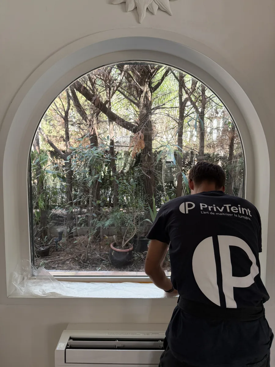 Technicien PrivTeint en t-shirt de la marque posant un film sur une fenêtre cintrée à Hyères